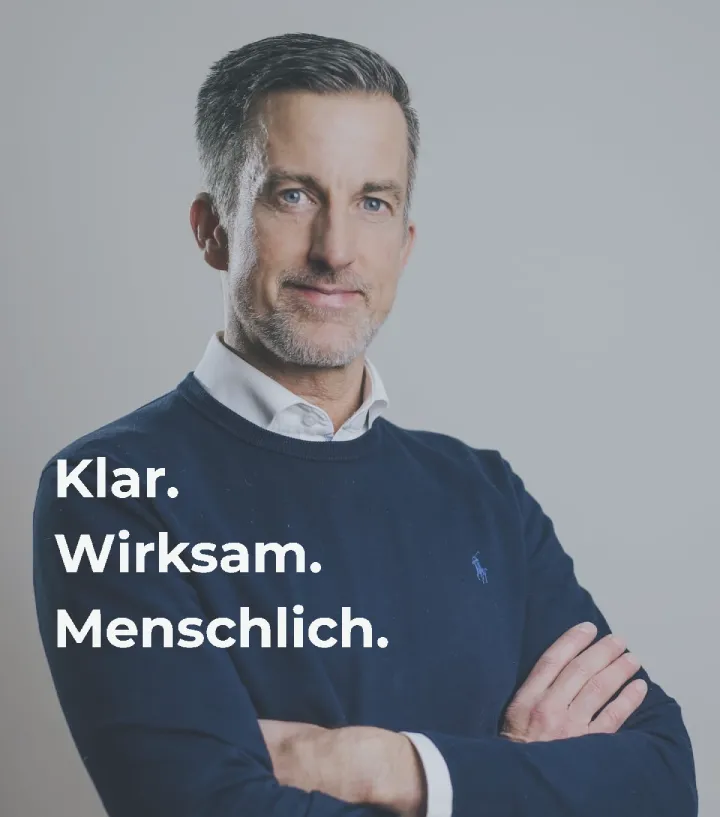 Porträt von Oliver Kober mit verschränkten Armen vor grauem Hintergrund – professionell, souverän und nahbar